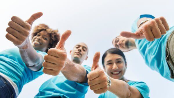 four people all giving thumbs up